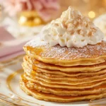 A stack of snickerdoodle pancakes topped with whipped cream and maple syrup on a royal-themed breakfast table