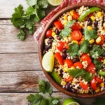 Colorful cowboy caviar couscous salad with diced vegetables, black beans, and lime dressing in a bowl